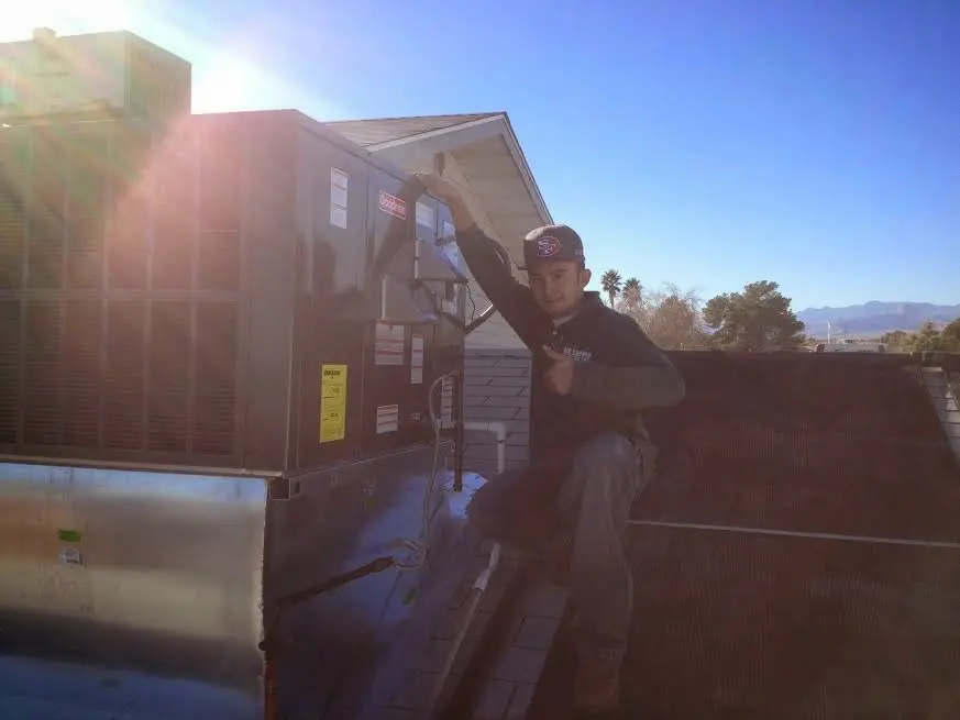 HVAC technician performing AC Tune-Up on a rooftop unit in Bright