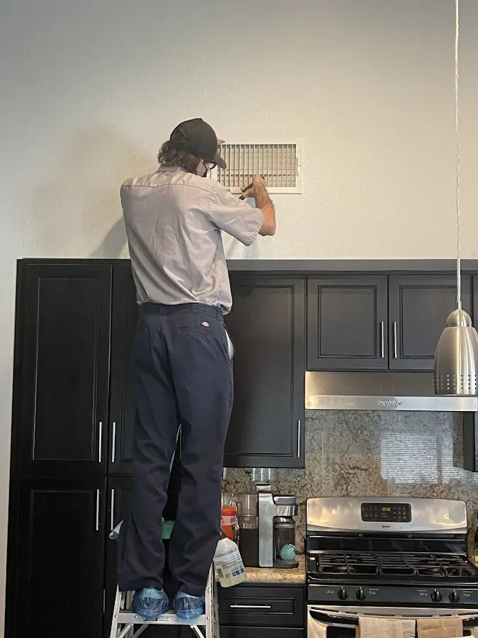 Technician inspecting an air vent during HVAC service in Bright